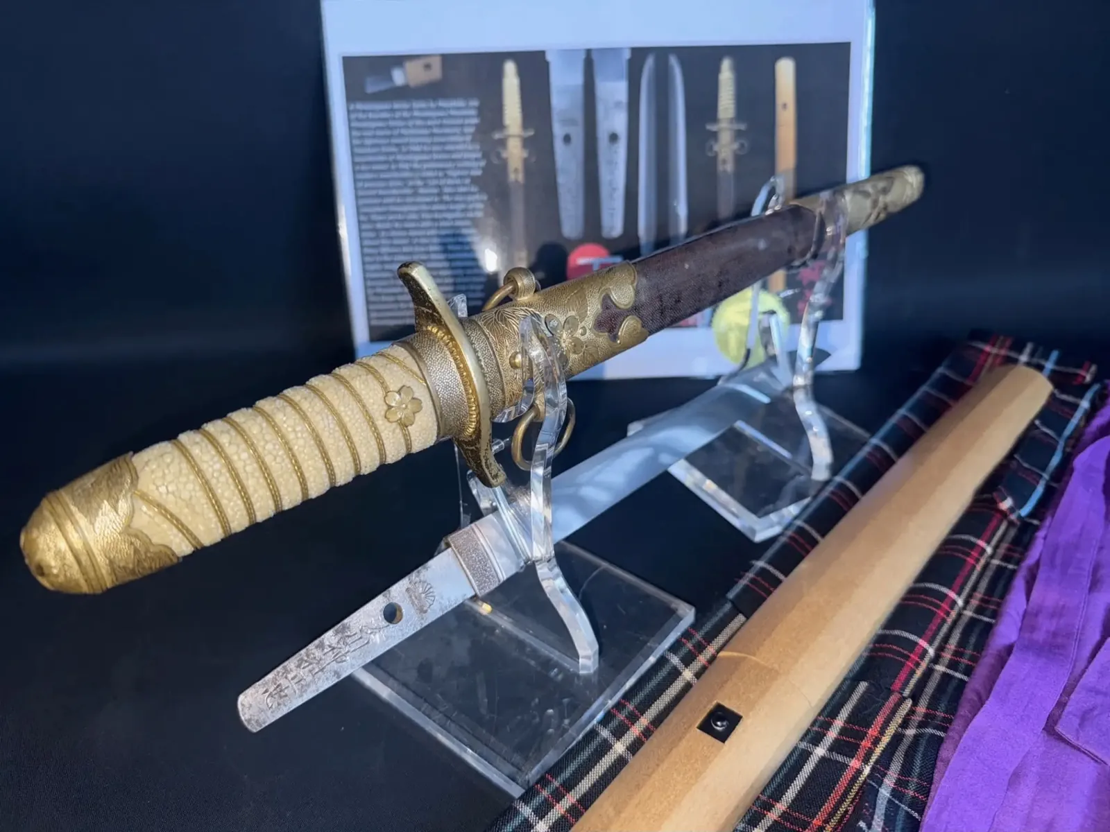 Side view of the Imperial Japanese Navy dirk koshirae for the Masatada tantō with gilt sakura fittings, same wrapped tsuka, brown lacquer saya and matching shirasaya on plaid cloth